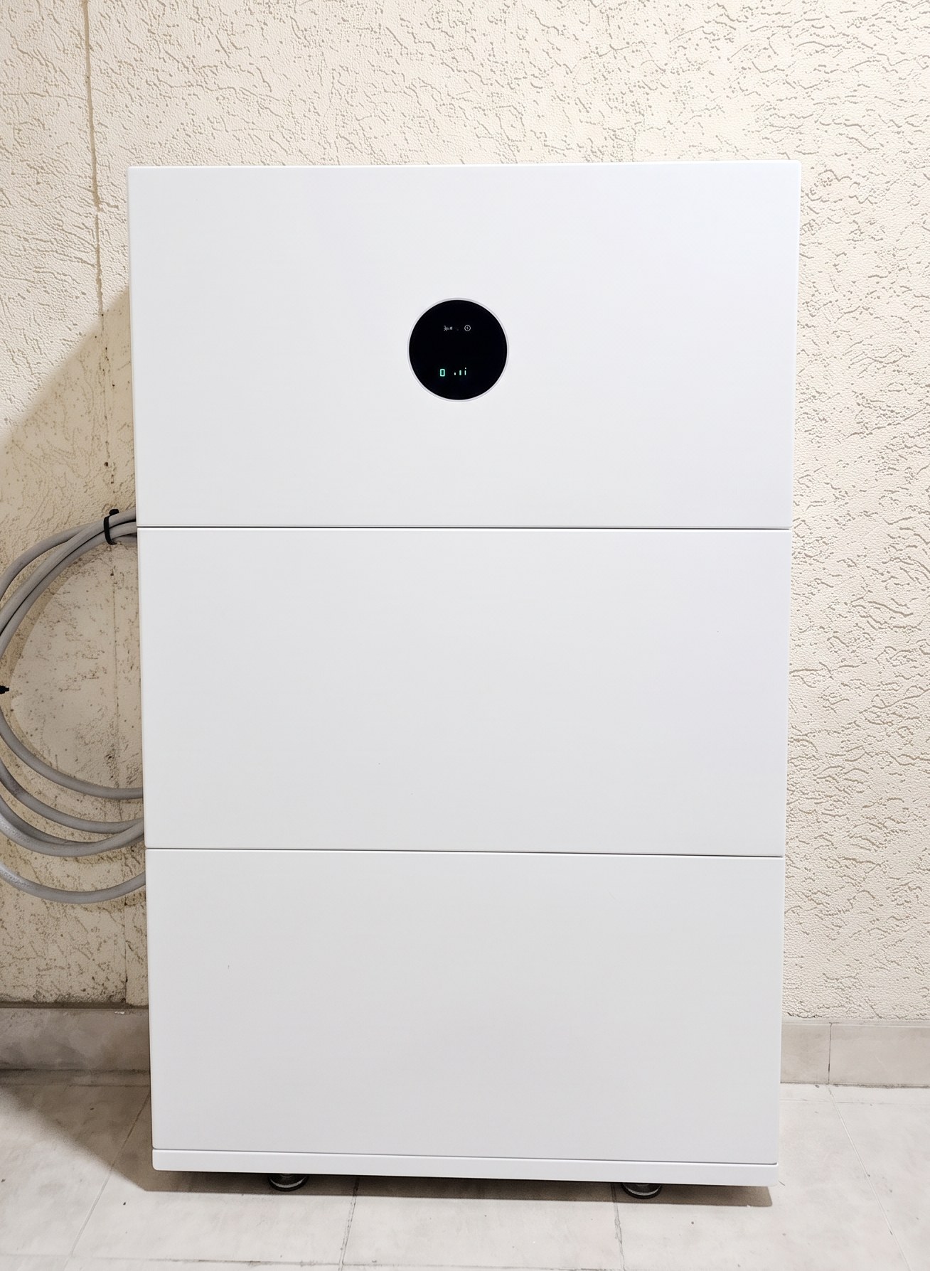 Front view of a stacked residential battery system with a round status display